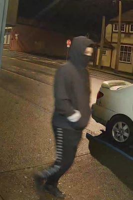 suspect 02, appears to be a male, dressed in a black hoodie with black pants that have while lines down the side of the legs. 