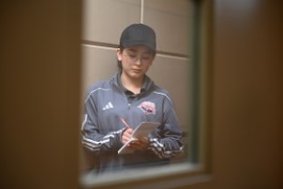 Une élève de l’École de gendarmerie pour la jeunesse portant une casquette de baseball prend des notes dans un calepin.