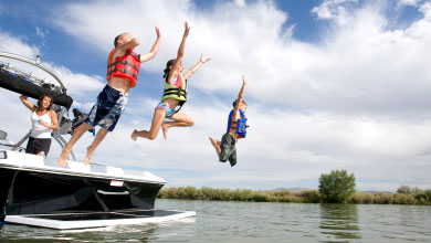 Kids wearing lifejackets and jumping off a boat