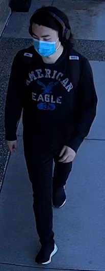Homme asiatique, portant un chandail à capuchon de marque American Eagle, un pantalon noir, un masque médical bleu, des écouteurs noirs