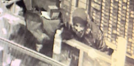 Une image en noir et blanc d'un suspect derrière un comptoir de vente au détail.