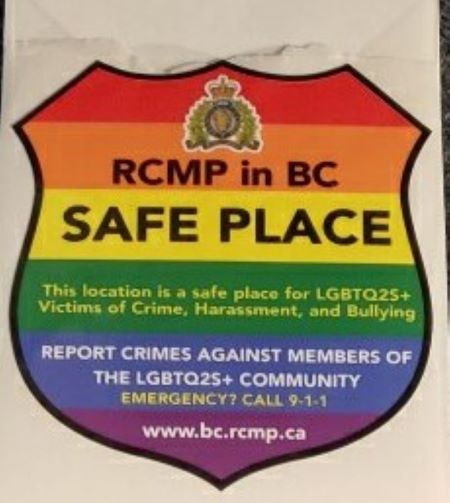 Rainbow stickers in the shape of police badges, with the RCMP crest and text announcing the displayer as an RCMP in BC Safe Place. 