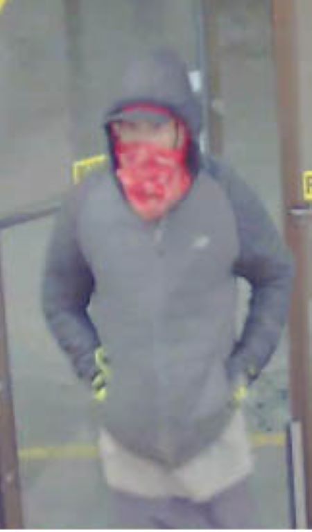 Suspect vu de face : un homme de corpulence moyenne portant un masque intégral rouge, un chandail à capuchon noir, un pantalon noir et des gants ayant du jaune fluorescent.