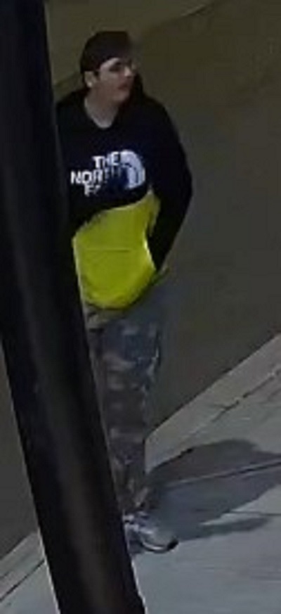 male youth suspect with short dark hair wearing glasses, a black and yellow <q>The North Face</q> hoodie with camouflage pants.