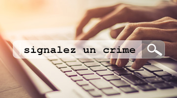 Doigts qui touchent un clavier et qui tapent les mots « signalez un crime ».